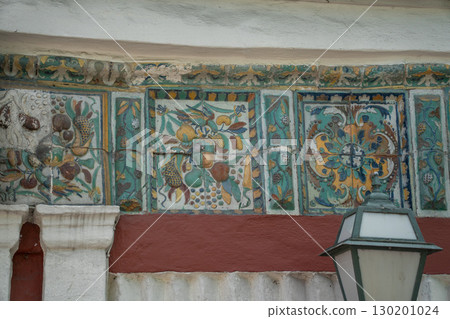 Ornate ceramic tilework featuring a winged seraphim face, floral motifs, and Orthodox Christian symbols in rich green, yellow, blue, and red tones Ornate ceramic tilework featuring a winged seraphim face, floral motifs, and Orthodox Christian symbols in rich green, yellow, blue, and red tones 130201024