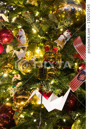 A decorated tree featuring a maneki-neko, gold cat, red and gold balls, paper crane, and festive lights A decorated tree featuring a maneki-neko, gold cat, red and gold balls, paper crane, and festive lights 130201045