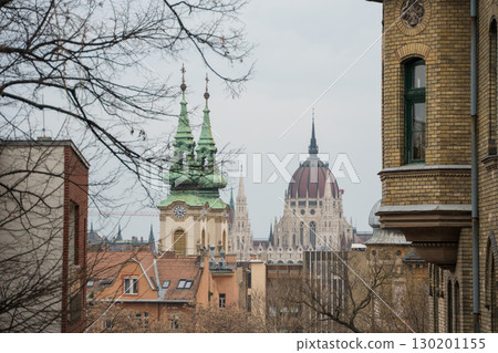 View of the green copper towers of St. Anne Church and the iconic dome of the Hungarian Parliament Building in Budapest 130201155