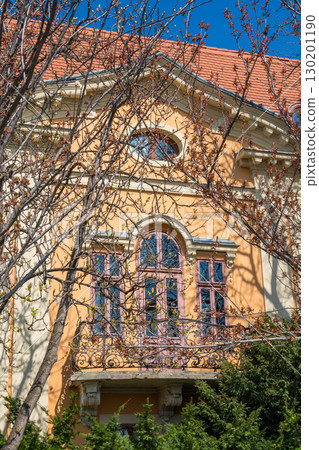 Elegant peach-colored villa in Budapest with ornate pink window frames and wrought iron balcony 130201190