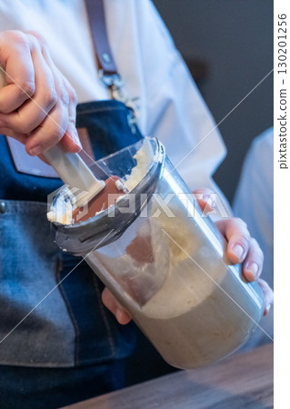 A woman is ready to spread cinnamon rolls cream with a silicone spatula 130201256