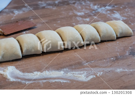 A rolled yeast dough is cut into slices for making cinnamon rolls A rolled yeast dough is cut into slices for making cinnamon rolls 130201308