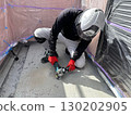 A male craftsman using a sander to prepare the base for waterproofing a balcony 130202905