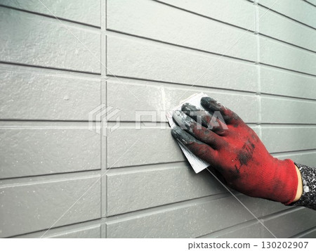 Sanding the exterior wall to touch up the paint 130202907