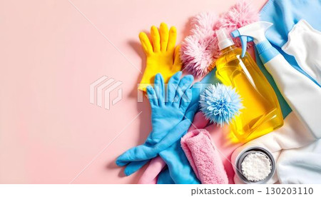An arrangement of bright cleaning supplies in a flat lay on a pink background, showcasing a collection of colorful bottles and tools 130203110