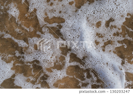 White sea foam created by waves crashing on the shore. Natural marine background White sea foam created by waves crashing on the shore. Natural marine background 130203247