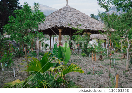Gazebo with a thatched roof in the open air in a tropical garden for yoga. Veranda or terrace in Asian style for sports 130203268