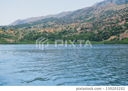 Crystal clear water of the freshwater Lake Kournas in Crete near Georgioupolis. Mountain view. Clouds reflected in the water Crystal clear water of the freshwater Lake Kournas in Crete near Georgioupolis. Mountain view. Clouds reflected in the water 130203282