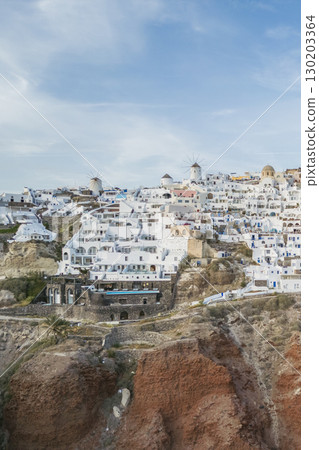 Drone view of the most touristy town Oia on Santorini, amazing shot showing dense construction on a steep cliff 130203364