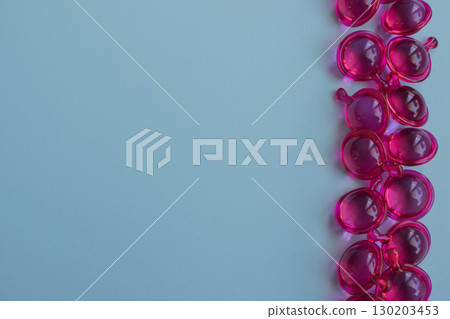Pink hair vitamin capsules on a light blue background with copy space 130203453