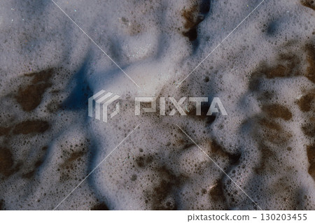 White sea foam created by waves crashing on the shore. Natural marine background White sea foam created by waves crashing on the shore. Natural marine background 130203455