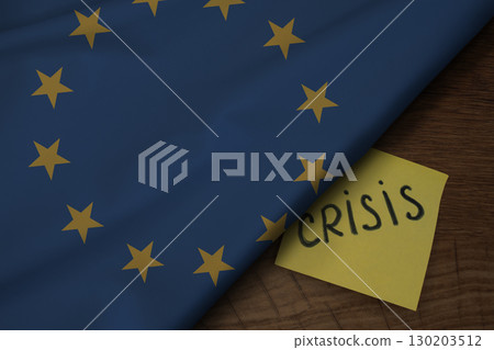 Fabric of the European Union flag on wooden surface and the word Crisis, concept of tense crisis situation in the country Fabric of the European Union flag on wooden surface and the word Crisis, concept of tense crisis situation in the country 130203512