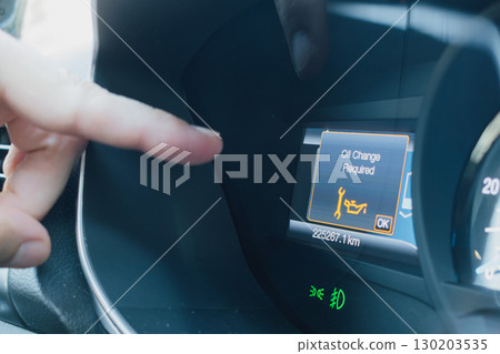 A male finger points to the oil change alert on a car dashboard display A male finger points to the oil change alert on a car dashboard display 130203535