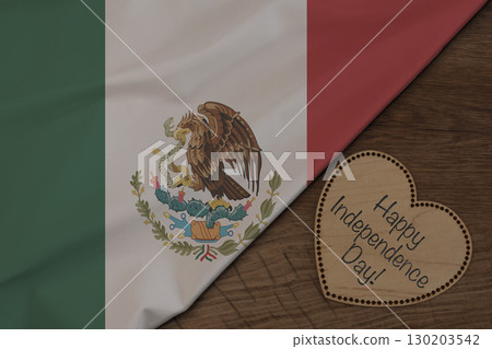 Mexican flag on wooden surface with Happy Independence Day on wooden heart 130203542