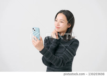 A smiling woman looking at a smartphone A smiling woman looking at a smartphone 130203698