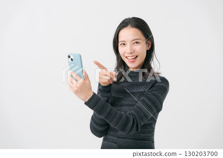 一個微笑的女人看著智能手機 130203700