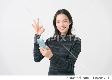 A smiling woman looking at a smartphone A smiling woman looking at a smartphone 130203701