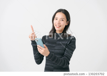 一個微笑的女人看著智能手機 130203702