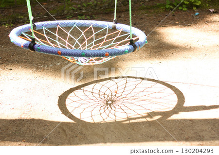 A swing-like playground equipment in a park and its shadow 130204293