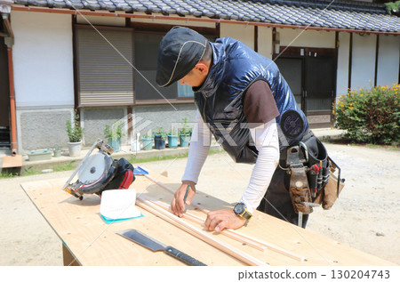 一位木匠正在工作台上用鉛筆在一塊木條上做標記 130204743