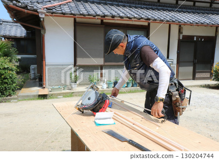 A carpenter is measuring wood with a convex scale on a workbench 130204744