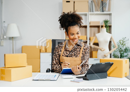Young business owner woman prepare parcel box and standing check online orders for deliver to customer Young business owner woman prepare parcel box and standing check online orders for deliver to customer 130205442