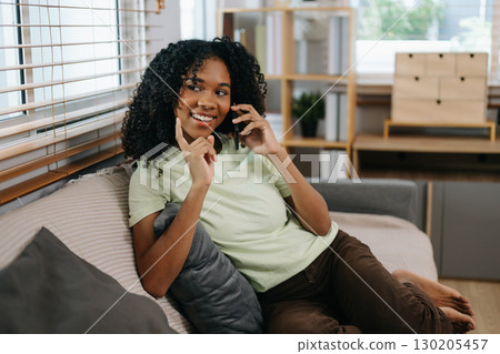 frican woman using the smartphone and tablet on the sofa at home frican woman using the smartphone and tablet on the sofa at home 130205457