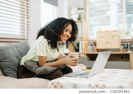 Young woman using a tablet in a cozy home, capturing creativity, relaxation, and digital connection 130205462