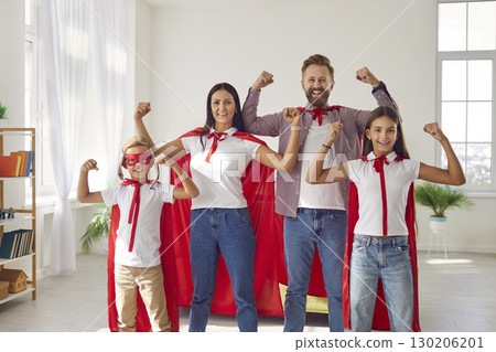 Happy family in superhero costumes standing with hands in fist and looking at camera at home. 130206201