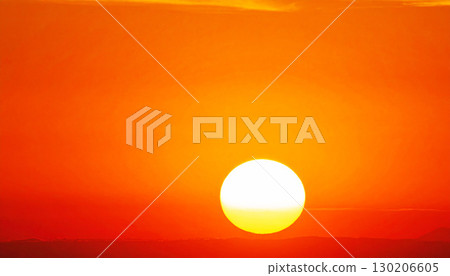 a bright yellow sun descending over the ocean horizon, against a smooth gradient from deep red to bright orange. This serene scene captures the tranquil beauty of a sunset or sunrise 130206605