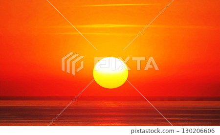 a bright yellow sun descending over the ocean horizon, against a smooth gradient from deep red to bright orange. This serene scene captures the tranquil beauty of a sunset or sunrise 130206606