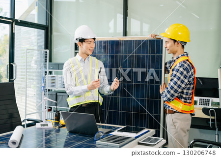 Two Asian engineers collaborate on a solar and wind energy project, discussing innovation and sustainability 130206748