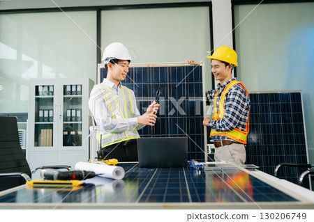 Two Asian engineers collaborate on a solar and wind energy project, discussing innovation and sustainability 130206749