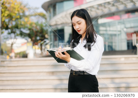 Successful businesswoman works outdoors near the office holds a tablet 130206970