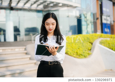 Successful businesswoman works outdoors near the office holds a tablet 130206971