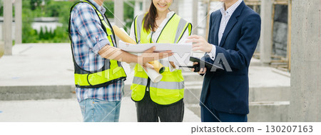 Contractor and architect looking at plan, tablet, laptop and talking about working on big project. Contractor and architect looking at plan, tablet, laptop and talking about working on big project. 130207163