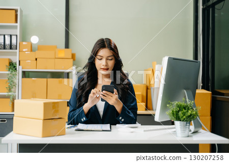 Young business owner woman prepare parcel box and standing check online orders for deliver to customer 130207258
