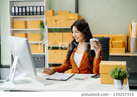 Young business owner woman prepare parcel box and standing check online orders for deliver to customer 130207359