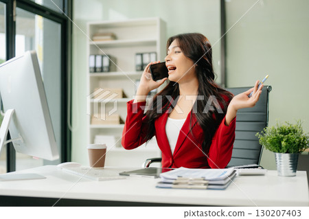 Asian woman using laptop and tablet while sitting at her working place 130207403