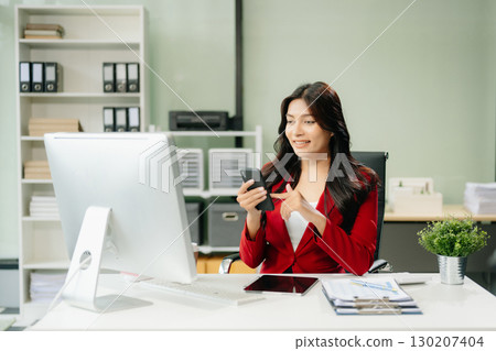 Asian woman using laptop and tablet while sitting at her working place 130207404