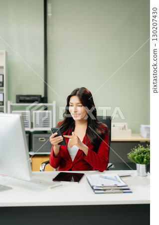 Asian woman using laptop and tablet while sitting at her working place 130207430