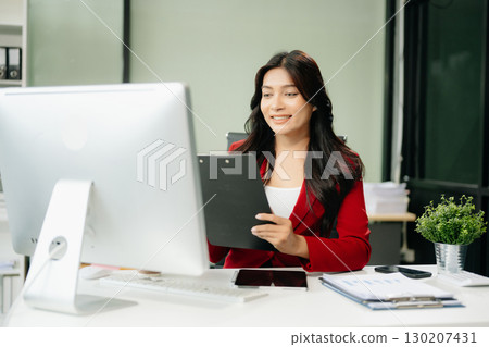 Asian woman using laptop and tablet while sitting at her working place 130207431