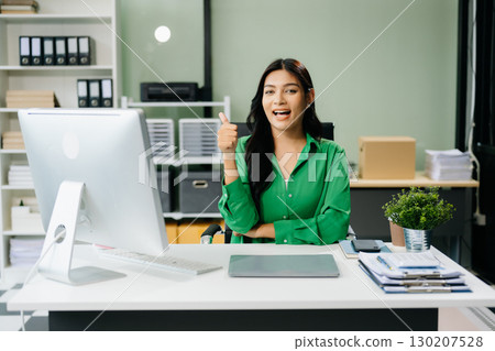 Young attractive Asian female office worker business suits smiling in office Young attractive Asian female office worker business suits smiling in office 130207528