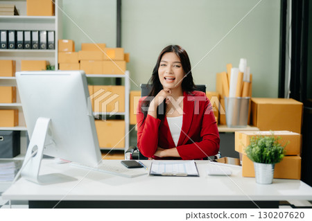 Asian woman prepares parcels and checks online orders on tablet and laptop for delivery online shopping Asian woman prepares parcels and checks online orders on tablet and laptop for delivery online shopping 130207620