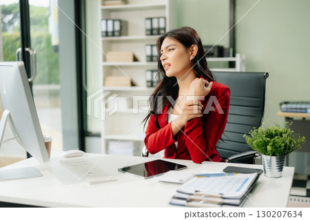 Overworked young Asian businesswoman office worker suffering from neck pain after had a long day 130207634