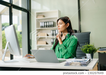 Young businesswoman working with working notepad, tablet and laptop documents talking on the smartphone, tablet 130207649