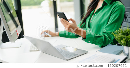 Confident businessman working on laptop, tablet and smartphone at her workplace 130207651