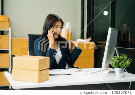 Young business owner woman prepare parcel box and standing check online orders for deliver to customer 130207671