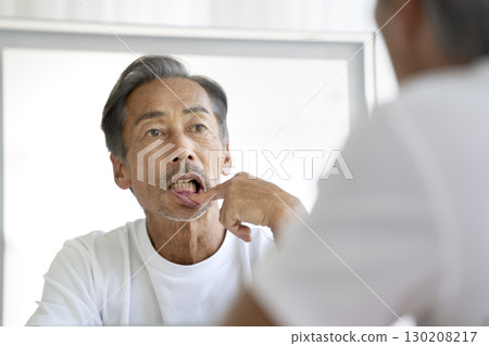 A man in his 60s who looks in the mirror and worries about his gums A man in his 60s who looks in the mirror and worries about his gums 130208217