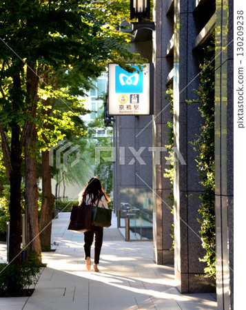 A woman walking on a sidewalk near the entrance to Kyobashi subway station in downtown Tokyo 130209238